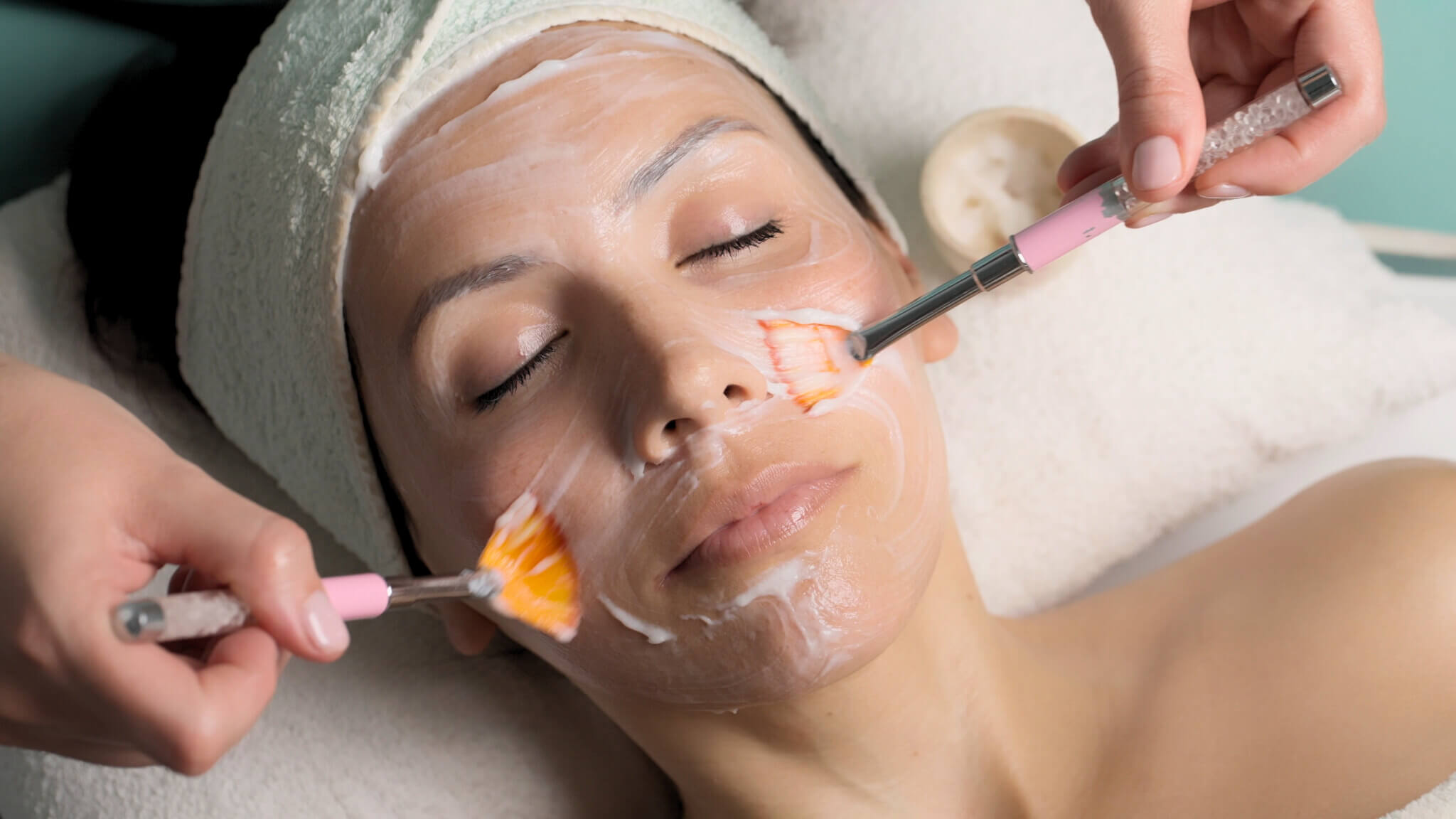 Tratamiento facial en spa aplicando crema con pinceles para rejuvenecimiento de la piel.
